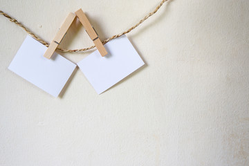 Three squares of blank paper, pegged to a string washing line, with wood plank fence in the background.