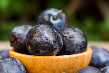 Fresh ripe plums in wooden bowl close