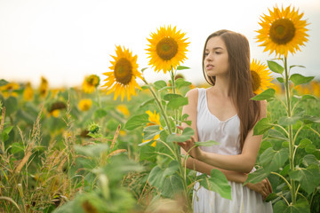 Obraz na płótnie Canvas beautiful girl in a field of sunflowers
