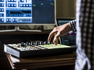 close up man's hand recording sound in recording music studio using new modern equipment with large monitor and laptop