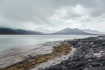 Tourists walk by the shore of the Laguna Blanca (white lagoon) in the Eduardo Avaroa National Reserve in Bolivia