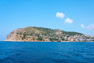 Fototapeta premium Island against a blue sky with clouds. Seaside of Alanya, Turkey. 
