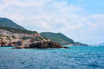 Fototapeta na wymiar Flag of Turkey on rocks in sea coast of Alanya. Cloudy blue sky. 