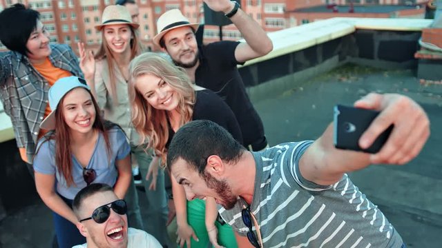 Group of happy student friends in shared posing for selfie laughing pulling faces and gesticulating