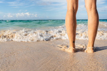 Young woman legs standing on sand on beach vacation