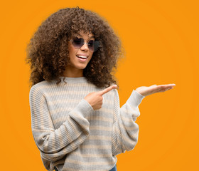 African american woman wearing a stripes sweater very happy pointing with hand and finger
