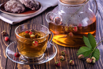 Fruit tea with wild berries in glass cup and dessert for breakfast on wooden background.Healthy drink with forest strawberry.