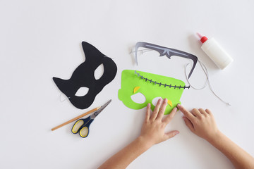 Making masks  paper  holiday Halloween Monster's  mask Black cat  Hands top view 