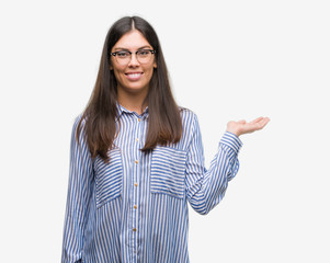 Young beautiful hispanic business woman smiling cheerful presenting and pointing with palm of hand...