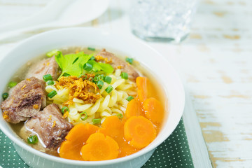 Macaroni soup with pork and carrot on white wooden table - delicious and healthy food concept
