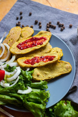 Crispy corn breads slices. Spicy and tasty on plate with green salad leaves, onion rings and tomatoes. Vegan lunch or vegetarian dinner. Healthy food concept.
