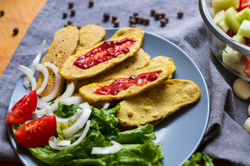 Crispy corn breads slices. Spicy and tasty on plate with green salad leaves, onion rings and tomatoes. Vegan lunch or vegetarian dinner. Healthy food concept.