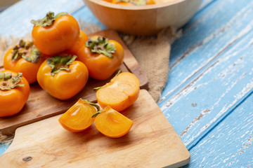 Fresh ripe persimmons on blue wooden table