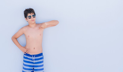 Young child on holidays standing over wall with surprise face pointing finger to himself