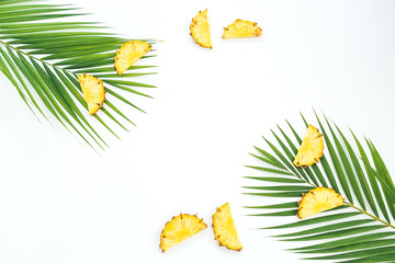 Fototapeta na wymiar Frame with sliced pineapple fruits and palm leaves on white background. Flat lay, top view. Tropical concept.