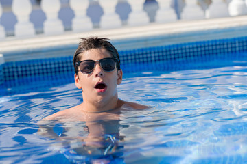 Young child on holiday at the swimming pool by the beach scared in shock with a surprise face,...