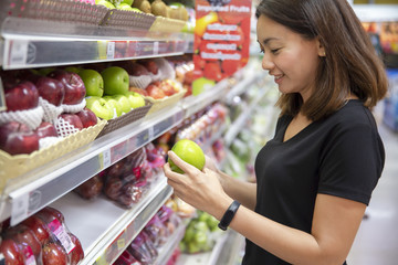 Beautiful girl happy with shopping fruits and vegetables in center supermarket