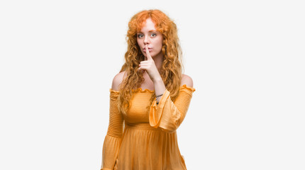 Young redhead woman asking to be quiet with finger on lips. Silence and secret concept.