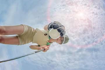 low and bottom view of golf ball in hand of young woman player taking from hole ground of the green with sky in background