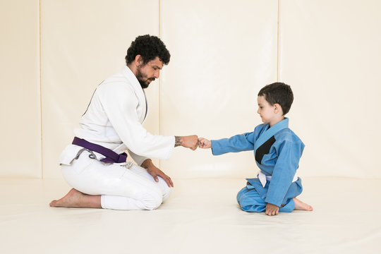 Male karate instructor training little child in dojo or jiu-jitsu at gym at tatami. Trainer teaches kid the basics of fighting for self-defense