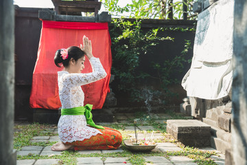 balinese woman praying at temple on small shrines in houses - obrazy, fototapety, plakaty