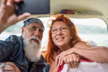  old hipster couple sitting in a van doing a selfie with a phone