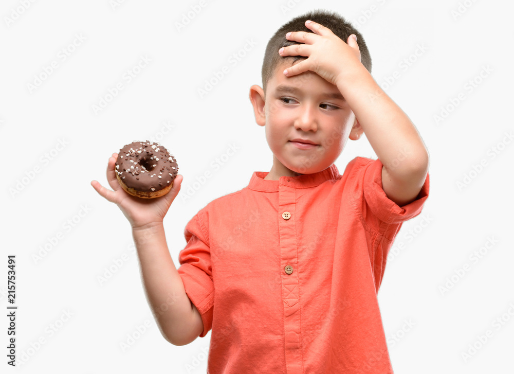 Canvas Prints Dark haired little child eating doughnut stressed with hand on head, shocked with shame and surprise face, angry and frustrated. Fear and upset for mistake.