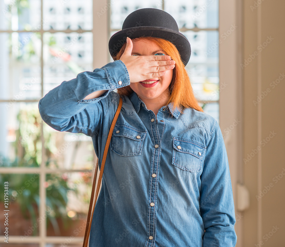 Sticker stylish redhead woman wearing bowler hat and sunglasses smiling and laughing with hand on face cover