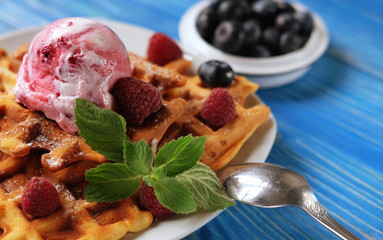 Plate of belgian waffles with ice cream and fresh berries - raspberries and blueberries.top view