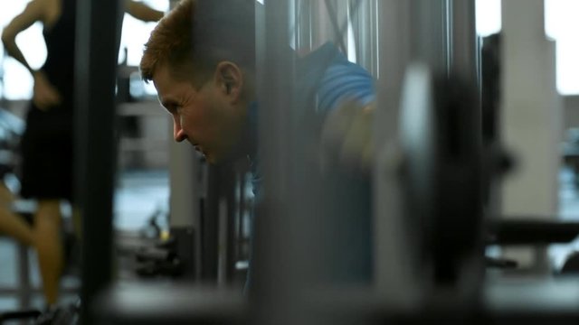 Tilt up with side view of focused paraplegic man in wheelchair doing chest fly exercise on cable machine in gym