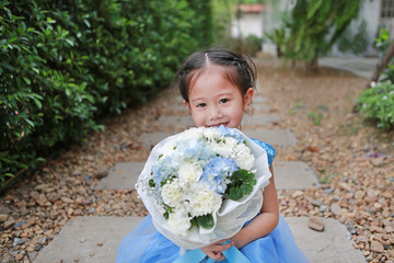 Fototapeta premium Cute little Asian child girl with Bouquet of flowers in the garden.