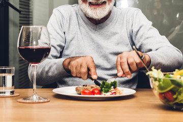 Happy senior man eating pork steak on table at restaurant
