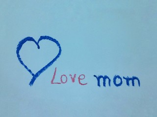 Drawing heart and write message Love mom on blue paper for Mother' Day.
