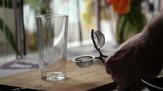 man preparing tea with glass of hot water and tea infuser. slow motion