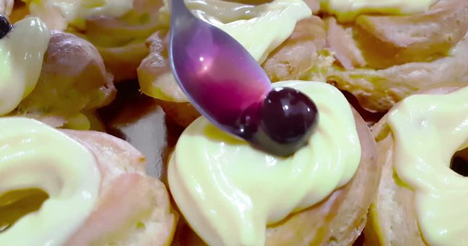 woman prepares delicious cream desserts called zeppole of St. Joseph and use the spoon for insert black cherry with syrup on top, italian traditional religious event,  party of daddy