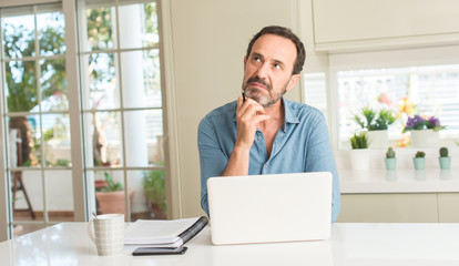 Middle age man using laptop at home serious face thinking about question, very confused idea - obrazy, fototapety, plakaty