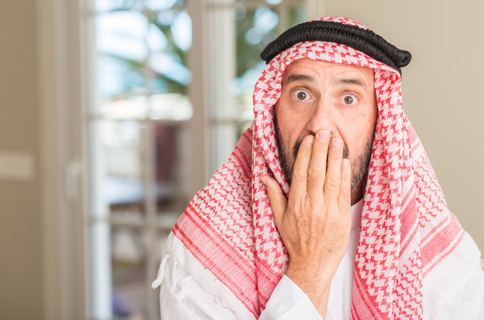 Middle age arabian man at home cover mouth with hand shocked with shame for mistake, expression of fear, scared in silence, secret concept