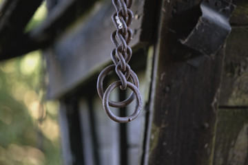 old metal forged chain hanging from an old wooden cart.