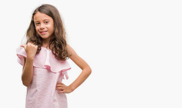 Brunette hispanic girl wearing pink dress smiling with happy face looking and pointing to the side with thumb up.