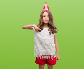 Brunette hispanic girl wearing birthday hat with surprise face pointing finger to himself