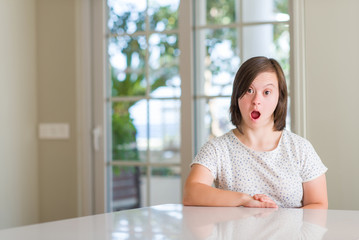 Down syndrome woman at home scared in shock with a surprise face, afraid and excited with fear expression