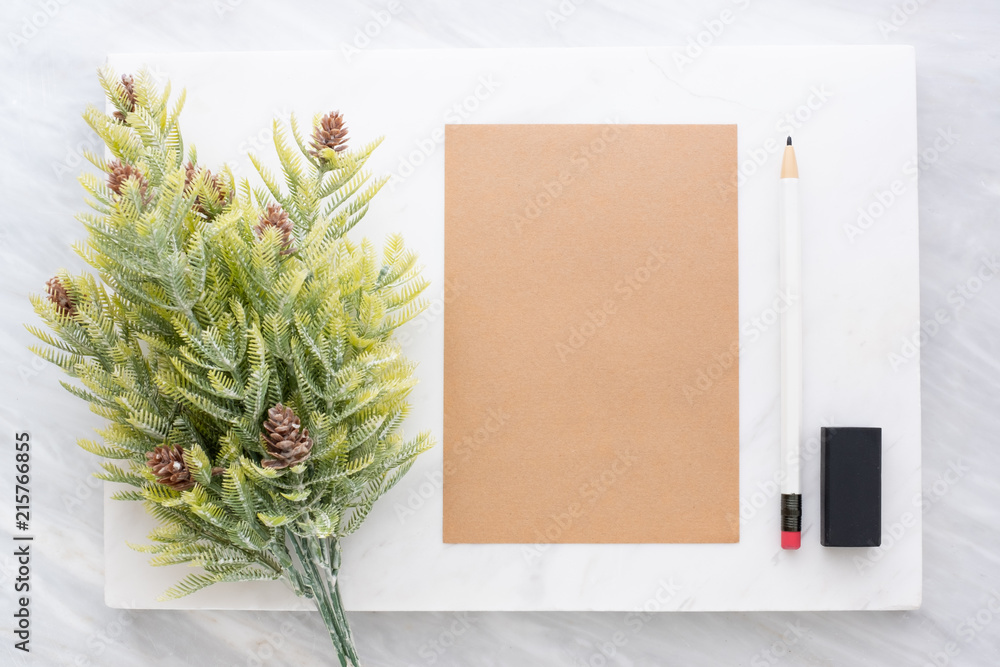 Poster Top view of pencil, eraser,fir leaf and brown  notepad on white marble block and stack on grey marble table.Flat lay Mock up template for adding or display text or design.Stationery item.