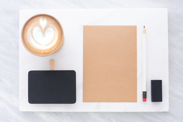 Top view of Clip blackboard, pencil, eraser notepad and coffee cup on white marble block and stack...