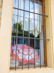 Hand-made laces and umbrella behind metal bars of shop window. Pano Lefkara, Cyprus.