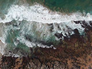Aerial photo of waves crashing on rocks