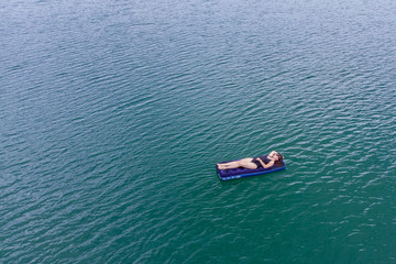woman on mattress in azure water. overhead view. copy space