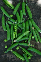 Fresh green peas in pods on a dark gray background. Rustic. Flat lay