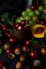 Assorted fruits. A dark still-life with fruits: grapes, peach, cherries.
