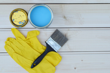 Blue paint in can, brush and yellow gloves on natural wooden planks background ready for painting or priming with waterborne colorless exterior wood preservative for timber protection top view image w