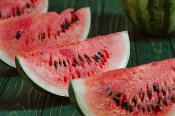 close up view of watermelon slices on green wooden surface